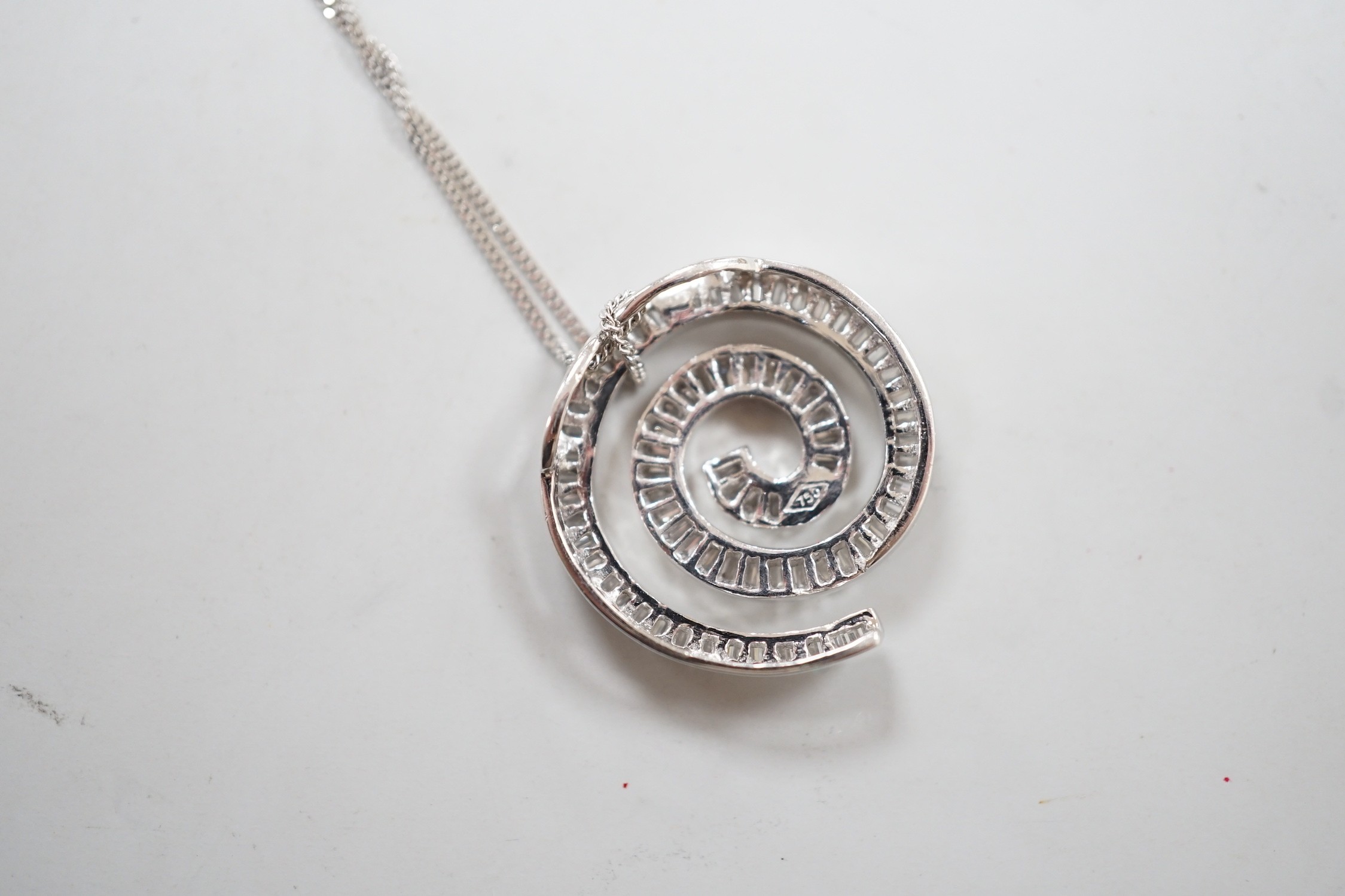 A modern 750 white metal and baguette cut diamond set whorl design pendant, 22mm, gross 4.5 grams, on a 9ct white gold fine link chain, 46cm, 1.1 grams.